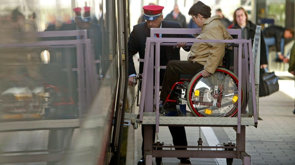 Ein Mitarbeiter der Deutschen Bahn hilft einer Frau, in den Zug zu gelangen