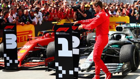 Sebastian Vettel beim Tauschen des Siegeraufstellers vor den Formel-1-Wagen.