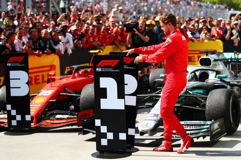 Sebastian Vettel beim Tauschen des Siegeraufstellers vor den Formel-1-Wagen.