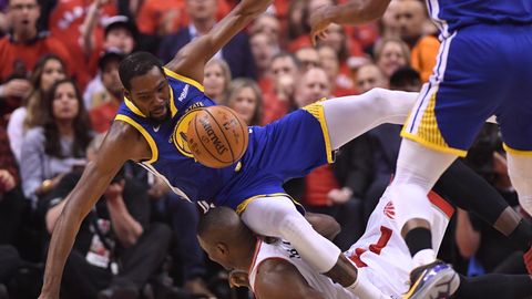 Kevin Durant (l.) von den Golden State Warriors fällt über den Toronto Raptors-Spieler Serge Ibaka