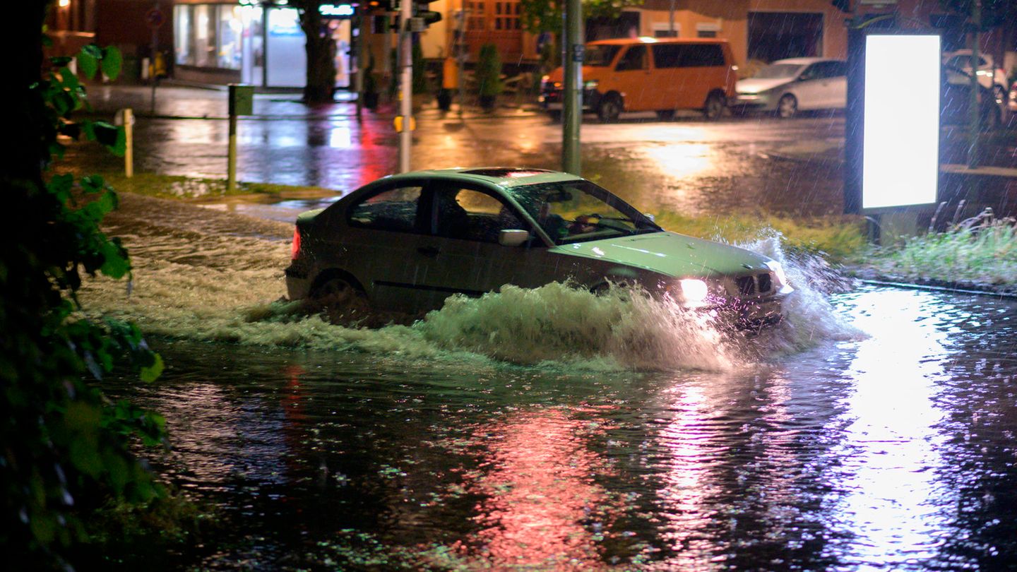 Ein Pkw fährt nach einem Gewitter mit heftigem Regen durch die überflutete Breite Straße in Berlin-Schmargendorf