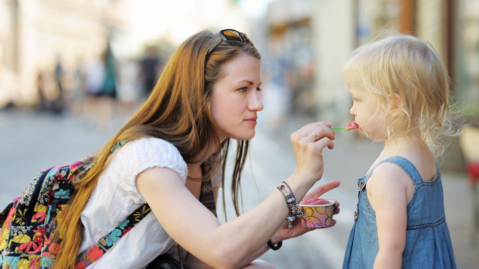 Eine Frau füttert ein Kind mit Eis