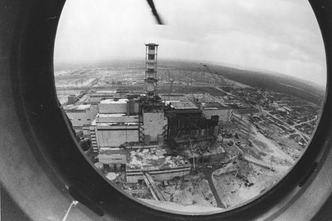 Ein Schwarz-weiß-Foto zeigt den explodierten Reaktor von Tschernobyl durch ein rundes Hubschrauber-Fenster