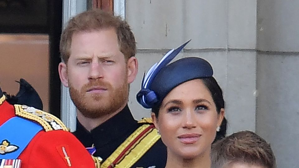 Prinz Harry steht hinter seiner Frau, Herzogin Meghan, und schaut streng