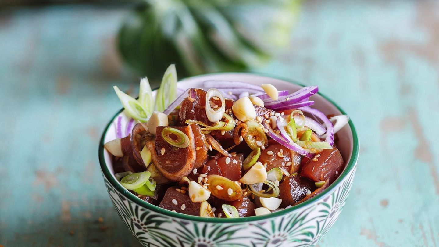Ahi Poke - Thunfischsalat  300 g Thunfisch (Sashimiqualität), 1 kleine rote Zwiebel, 2 Frühlingszwiebeln, 1 EL Macadamianusskerne, 2 TL Sesam, 2 EL Sojasoße, 1 EL Sesamöl, 1 EL Sriracha (Chilisoße), 1 TL Honig, Salz      Zubereitung:  Den Thunfisch waschen und trocken tupfen, anschließend in mundgerechte Würfel von ca. 2 3 2 cm schneiden. Die Zwiebel schälen, halbieren und in dünne Streifen schneiden. Die Frühlingszwiebeln putzen, waschen und in feine Ringe schneiden. Die Nüsse grob hacken. Eine kleine Pfanne ohne Fett erhitzen. Nüsse und Sesam in der heißen Pfanne knapp 1 Minute goldbraun rösten, bis sie zu duften beginnen. Dann gleich aus der Pfanne nehmen, damit sie durch die Resthitze nicht verbrennen, und abkühlen lassen.      Den Fisch mit je der Hälfte der Zwiebeln, der Nüsse und des Sesams in eine Schüssel geben. Sojasoße, Öl, Sriracha und Honig dazugeben und alles miteinander vermischen. Der Fisch soll von einer glänzenden Schicht aus Marinade überzogen sein. Nach Belieben mit etwas Salz abschmecken und in zwei Schalen abfüllen. Mit restlichen Zwiebeln, Nüssen und Sesam bestreuen und servieren.