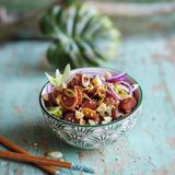 Ahi Poke - Thunfischsalat  300 g Thunfisch (Sashimiqualität), 1 kleine rote Zwiebel, 2 Frühlingszwiebeln, 1 EL Macadamianusskerne, 2 TL Sesam, 2 EL Sojasoße, 1 EL Sesamöl, 1 EL Sriracha (Chilisoße), 1 TL Honig, Salz      Zubereitung:  Den Thunfisch waschen und trocken tupfen, anschließend in mundgerechte Würfel von ca. 2 3 2 cm schneiden. Die Zwiebel schälen, halbieren und in dünne Streifen schneiden. Die Frühlingszwiebeln putzen, waschen und in feine Ringe schneiden. Die Nüsse grob hacken. Eine kleine Pfanne ohne Fett erhitzen. Nüsse und Sesam in der heißen Pfanne knapp 1 Minute goldbraun rösten, bis sie zu duften beginnen. Dann gleich aus der Pfanne nehmen, damit sie durch die Resthitze nicht verbrennen, und abkühlen lassen.      Den Fisch mit je der Hälfte der Zwiebeln, der Nüsse und des Sesams in eine Schüssel geben. Sojasoße, Öl, Sriracha und Honig dazugeben und alles miteinander vermischen. Der Fisch soll von einer glänzenden Schicht aus Marinade überzogen sein. Nach Belieben mit etwas Salz abschmecken und in zwei Schalen abfüllen. Mit restlichen Zwiebeln, Nüssen und Sesam bestreuen und servieren.