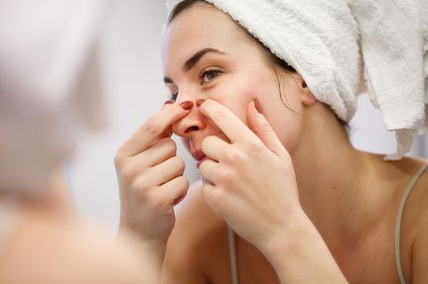 Reflexion der Frau mit Handtuch auf dem Kopf drücken Blackhead auf ihrer Nasenseite