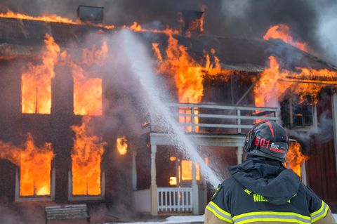 Ein Feuerwehrmann löscht ein brennendes Haus