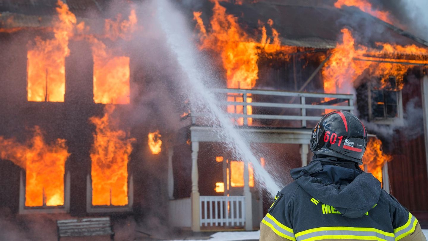 Ein Feuerwehrmann löscht ein brennendes Haus