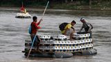 Flößer tragen eine Ladung Bier über den Rio Suchiate auf einem Schlauchboot