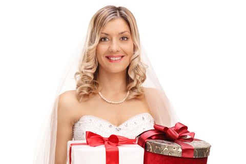 Blonde Braut hält drei Hochzeitsgeschenke in ihren Händen und grinst