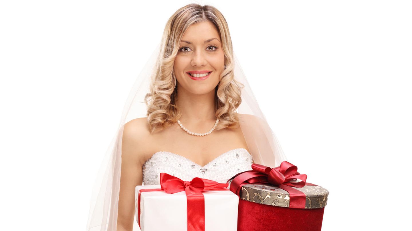 Blonde Braut hält drei Hochzeitsgeschenke in ihren Händen und grinst