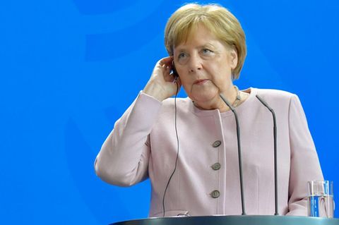 Angela Merkel mit Hand am Ohrhörer - kein Grund zur Sorge nach Zitter-Anfall