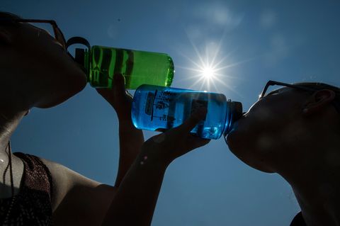 Zwei Frauen trinken bei Sonnenschein Wasser aus einer Flasche