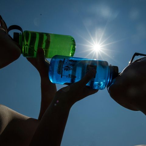 Zwei Frauen trinken bei Sonnenschein Wasser aus einer Flasche