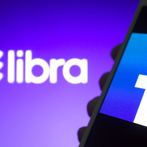 Das Libra-Logo ist vor einem Smartphone mit Facebook-Logo zu sehen