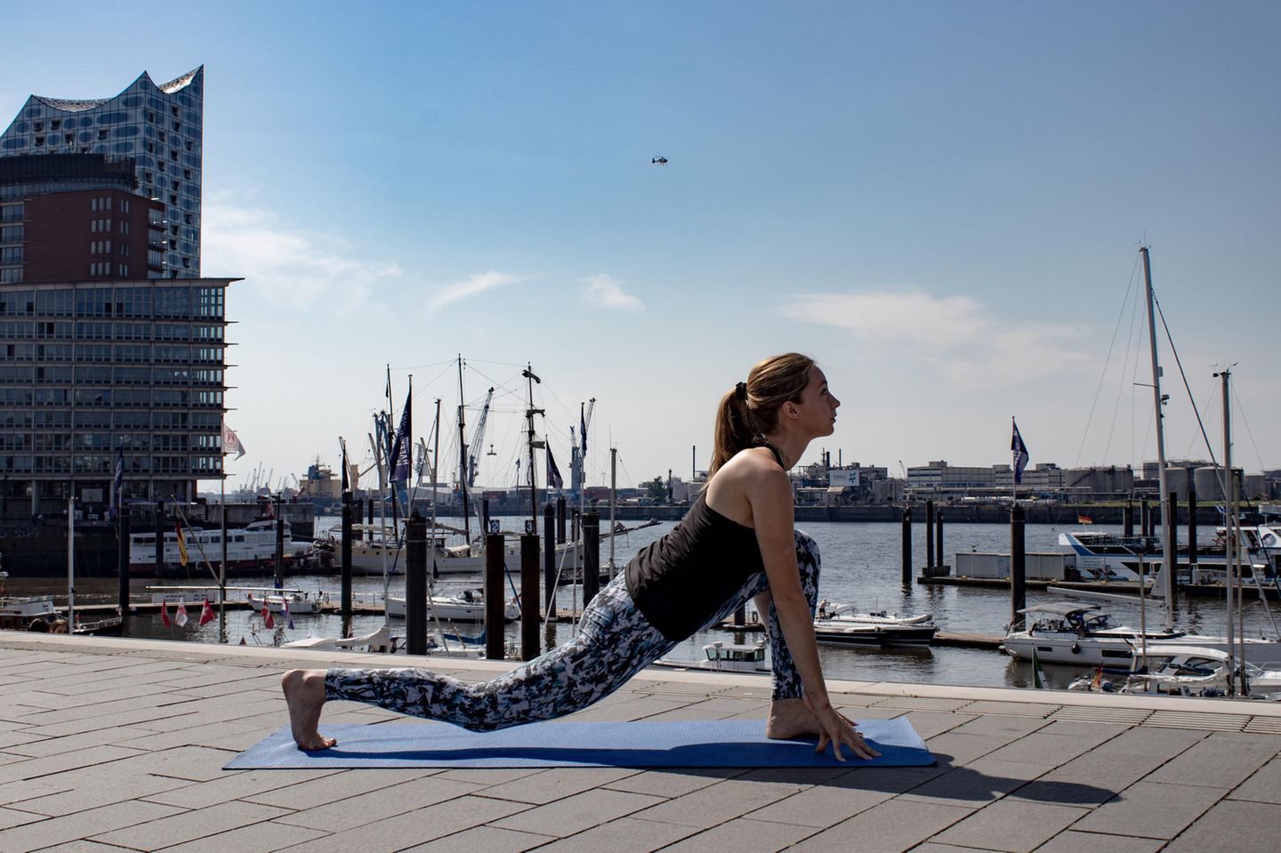 Strecke dein rechtes Bein nach hinten. Frau in Sportklamotten beim Yoga.