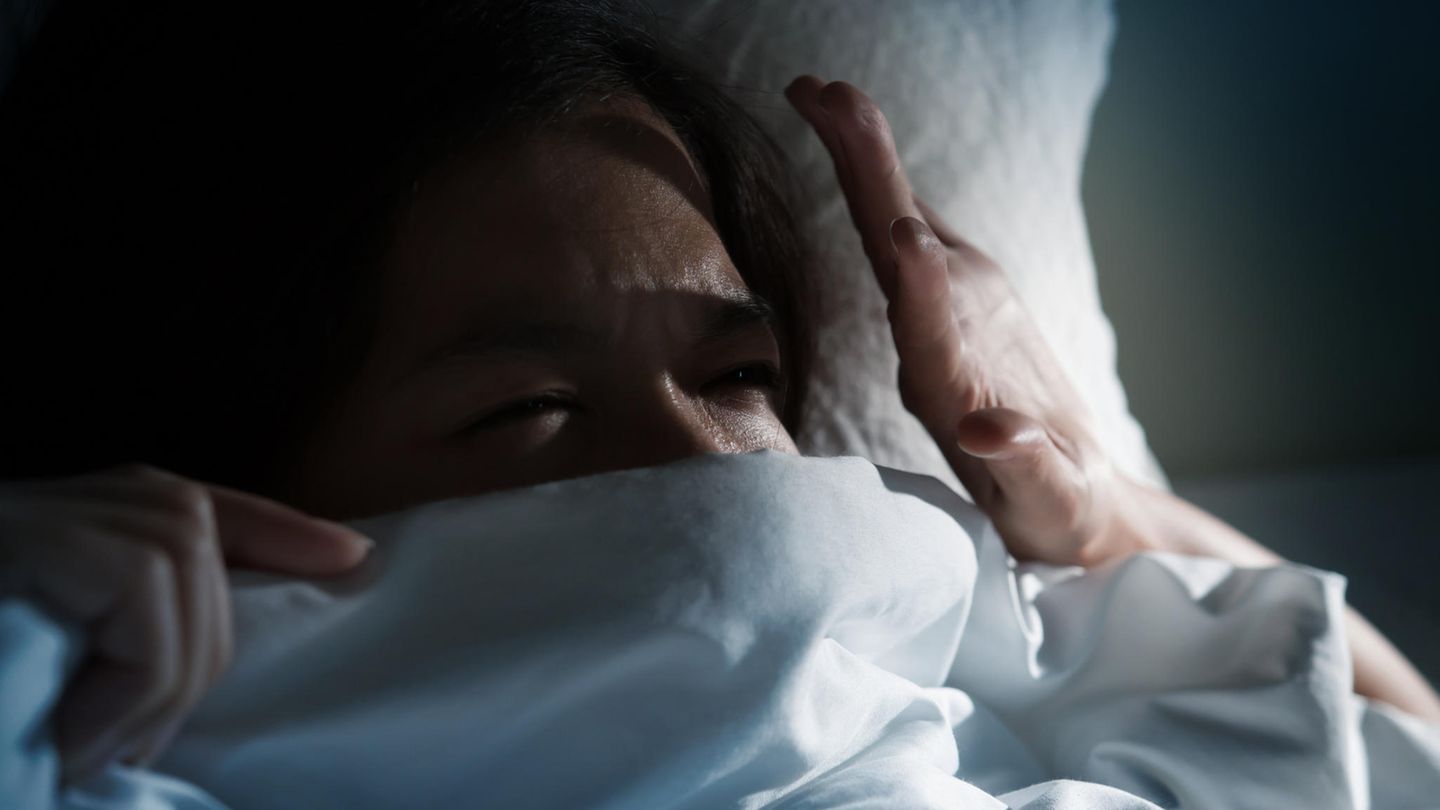 Frau im Bett im dunklen Zimmer