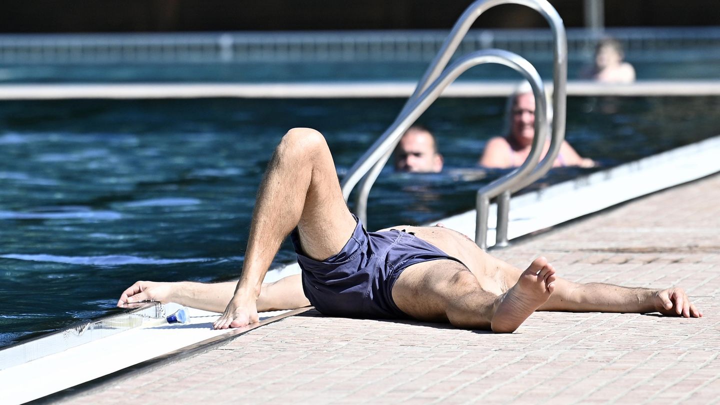 Ein Mann liegt auf dem Rücken am Rand eines Schwimmbeckens.