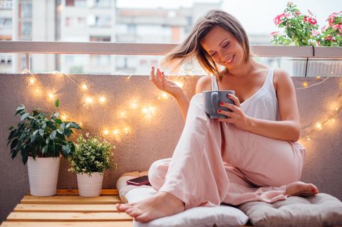 Frau mit Tasse auf dem Balkon