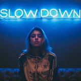 Neon-Schrift "Slow Down" und Frau mit ernstem Gesicht.