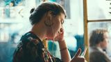 Frau schaut nachdenklich auf ein Handy.