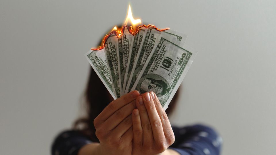 Frau mit brennenden Geldscheinen in der Hand