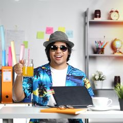 Mann am Schreibtisch mit Glas in der Hand