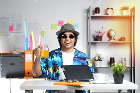 Mann am Schreibtisch mit Glas in der Hand