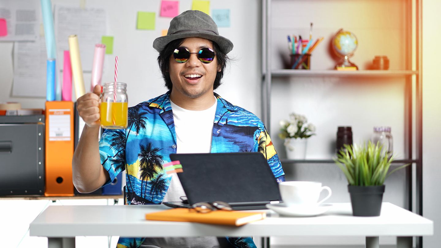 Mann am Schreibtisch mit Glas in der Hand