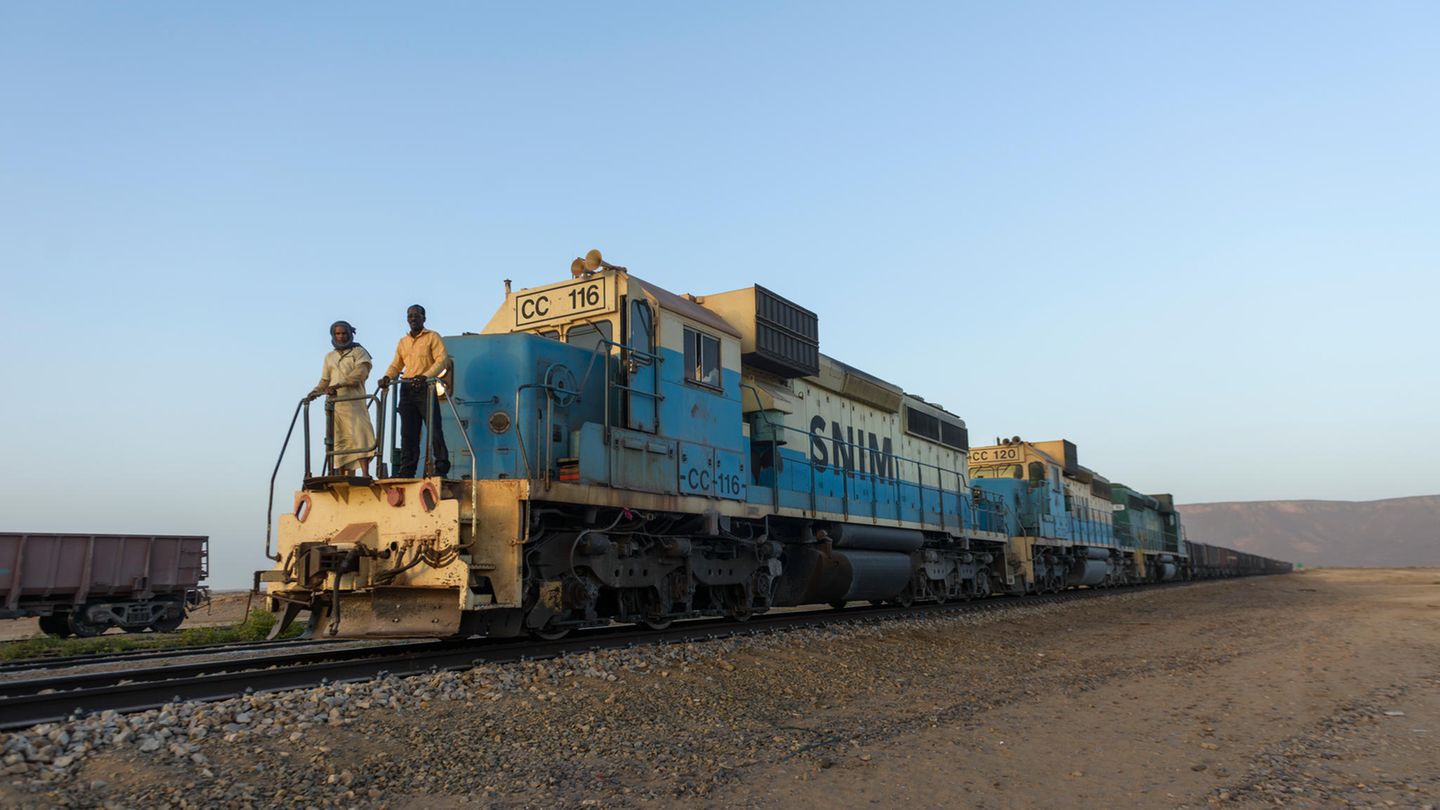 "500 Zugreisen": Mauretanien: Eisenerzzüge Einige der längsten Züge der Welt zuckeln durch die leeren Wüsten von Mauretanien. Sie bringen Eisenerz aus den Minen um Zouérat am Rand der Sahara über eine Strecke von 704 Kilometern nach Nouadhibou am Atlantik. Es gibt nur eine Eisenbahn in Mauretanien und die bis zu 2500 Meter langen Ungetüme wirken in der Sandwüste schon beeindruckend. Ansonsten sieht man hier bestenfalls kamelreitende Nomaden, entfernte Nachfahren der Mauren aus dem Berberkönigreich (300 v. Chr.–700 n. Chr.), denen das Land seinen Namen verdankt. Auf der Strecke verkehren ausschließlich Güterzüge, aber es kommt durchaus vor, dass blinde Passagiere auf einen Erzwaggon aufspringen. Mauretanien: Eisenerzzüge Einige der längsten Züge der Welt zuckeln durch die leeren Wüsten von Mauretanien. Sie bringen Eisenerz aus den Minen um Zouérat am Rand der Sahara über eine Strecke von 704 Kilometern nach Nouadhibou am Atlantik. Es gibt nur eine Eisenbahn in Mauretanien und die bis zu 2500 Meter langen Ungetüme wirken in der Sandwüste schon beeindruckend. Ansonsten sieht man hier bestenfalls kamelreitende Nomaden, entfernte Nachfahren der Mauren aus dem Berberkönigreich (300 v. Chr.–700 n. Chr.), denen das Land seinen Namen verdankt. Auf der Strecke verkehren ausschließlich Güterzüge, aber es kommt durchaus vor, dass blinde Passagiere auf einen Erzwaggon aufspringen.