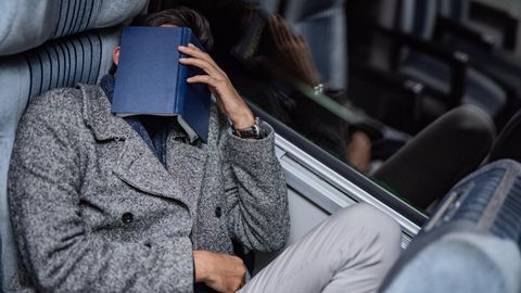 Mann mit Buch auf Gesicht schläft im Zug