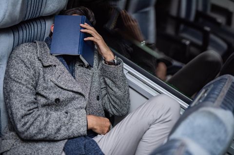 Mann mit Buch auf Gesicht schläft im Zug
