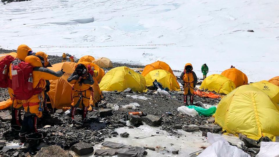 Mount Everest Basislager Zelte Bergsteiger Bergsteiger in dicken Jacken stehen im Basiscamp am Mount Everest zwischen lauter verlassenen Zelten.Im Hintergrund liegt Schnee