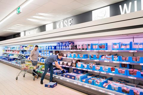 Mitarbeiter eines Supermarkts räumen Produkte ins Kühlregal