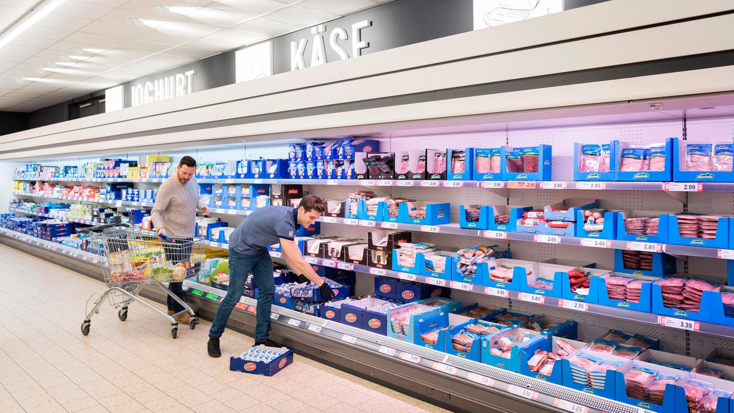 Mitarbeiter eines Supermarkts räumen Produkte ins Kühlregal
