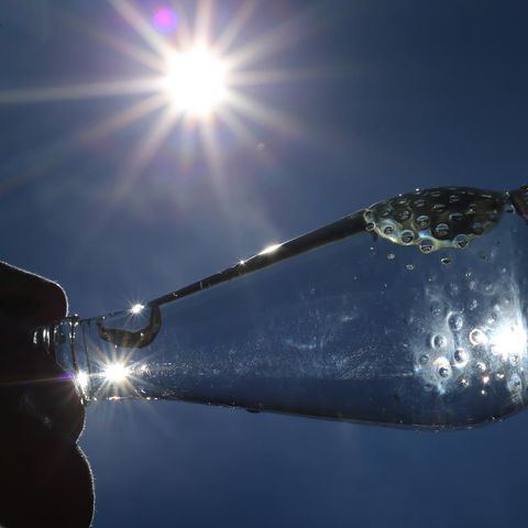 Hitzewelle – Frau trinkt bei Sonnenschein aus einer Wasserflasche