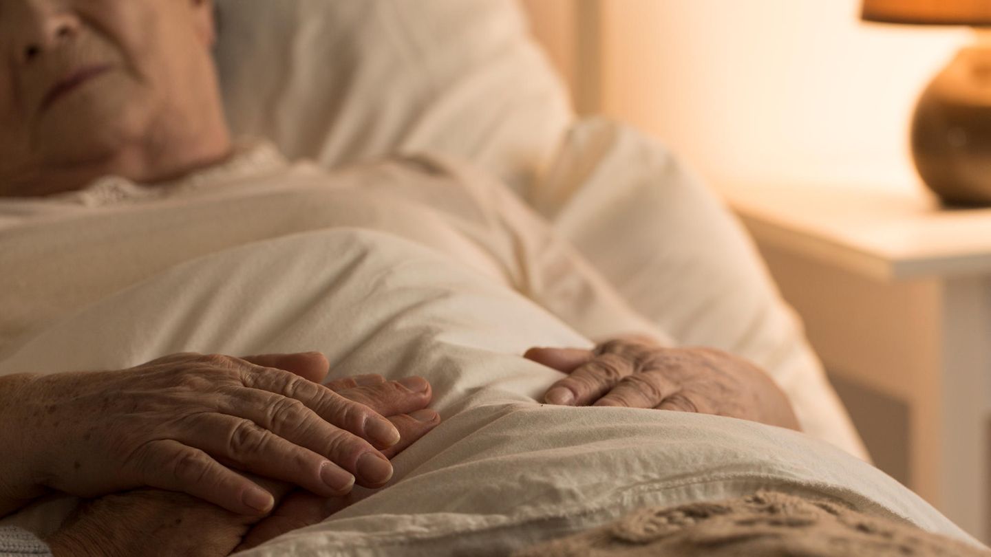 Ein gebrechlicher alter Mann liegt im Bett