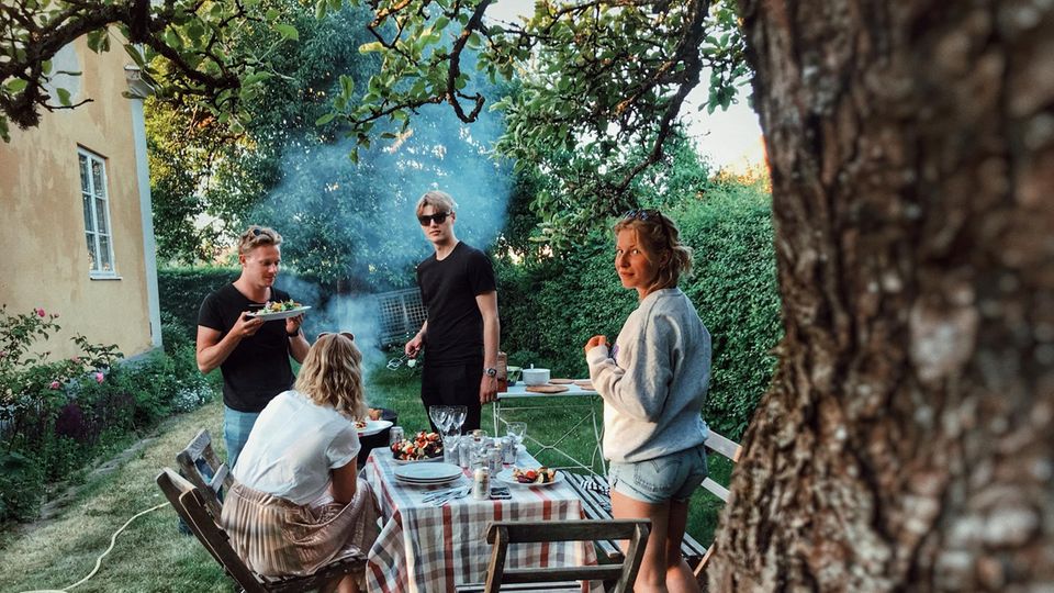 Freunde sitzen im Garten und grillen