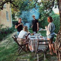 Freunde sitzen im Garten und grillen