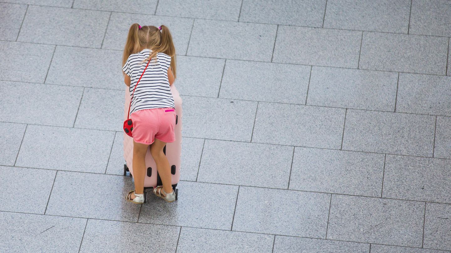 Ein kleines Mädchen schiebt einen Koffer durch einen Flughafen (Symbolbild)