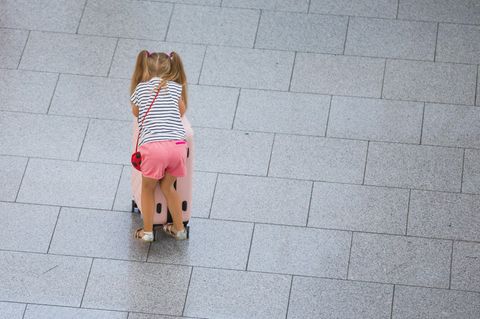 Ein kleines Mädchen schiebt einen Koffer durch einen Flughafen (Symbolbild)