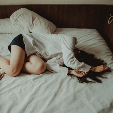 Frau liegt auf einem Bett.