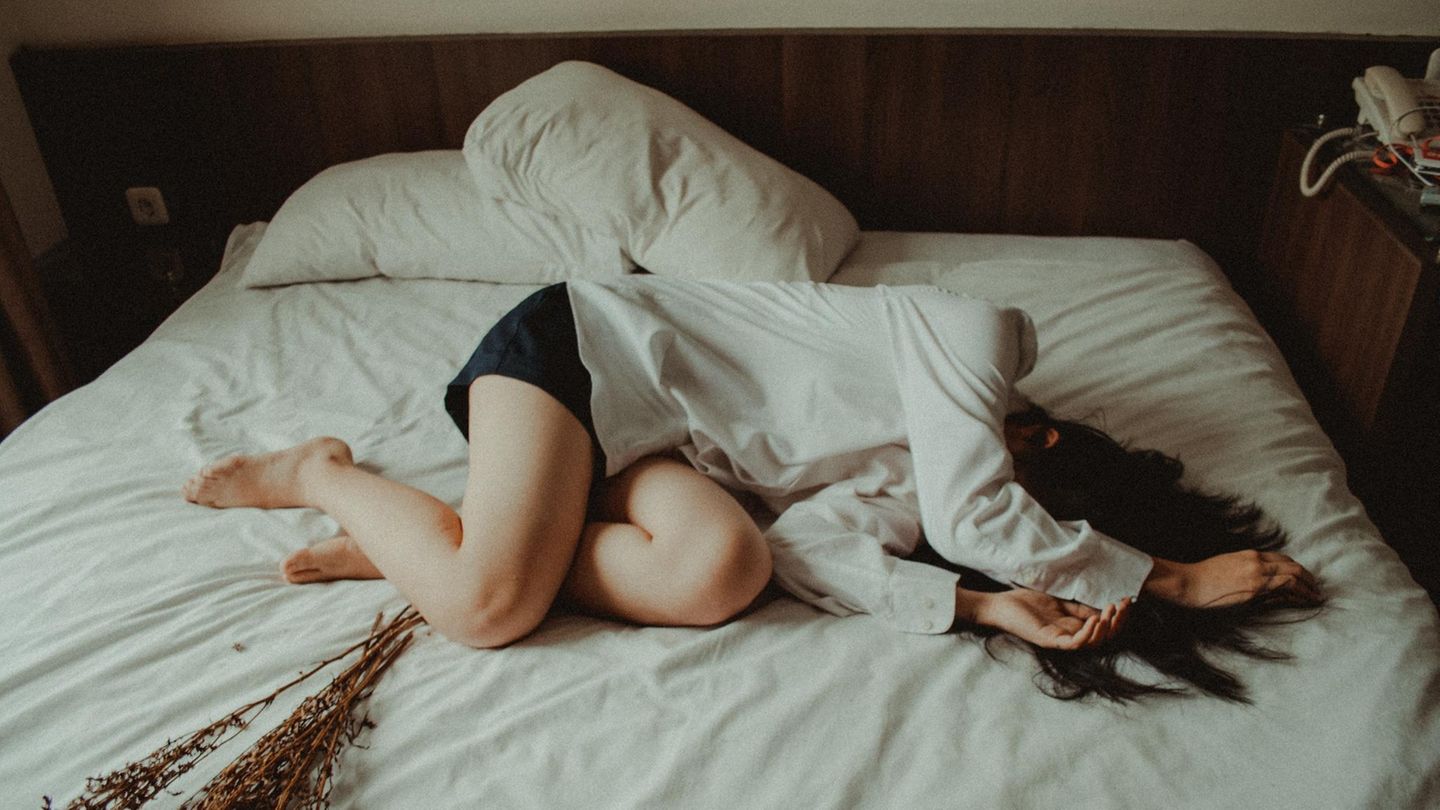 Frau liegt auf einem Bett.