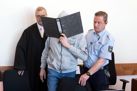 Der Angeklagte Andreas V. betritt mit einem Aktenordner vor dem Gesicht den Gerichtssaal