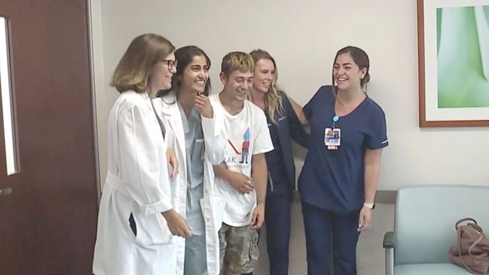 Eine Gruppe junger Menschen steht lachend in einem Krankenhaus, als wollten sie ein Gruppenfoto machen. Eine Gruppe junger Menschen steht lachend in einem Krankenhaus, als wollten sie ein Gruppenfoto machen.