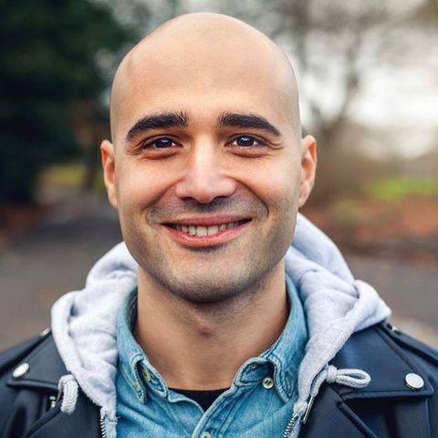 Ein glatzköpfiger Mann strahlt in die Kamera