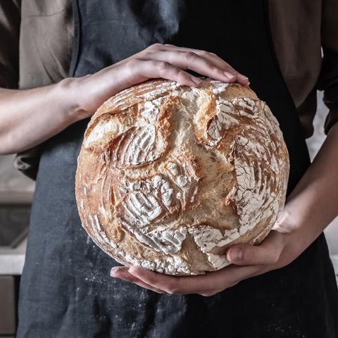 Ein Mensch hält ein rundes Brot in der Hand.