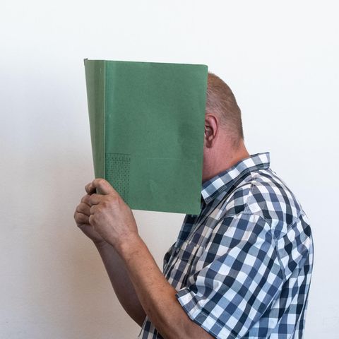 Heiko V. verdeckt sein Gesicht mit einer Aktenmappe.