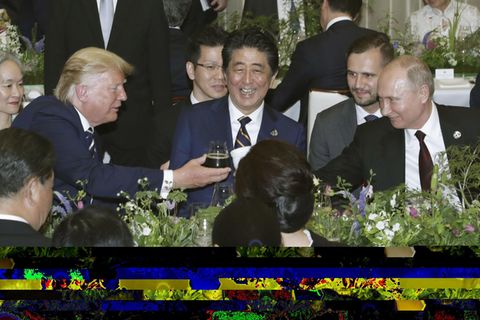 Leicht verdeckt sieht man hier US-Präsident Donald Trump und seinen russischen Amtskollegen Wladmir Putin anstoßen